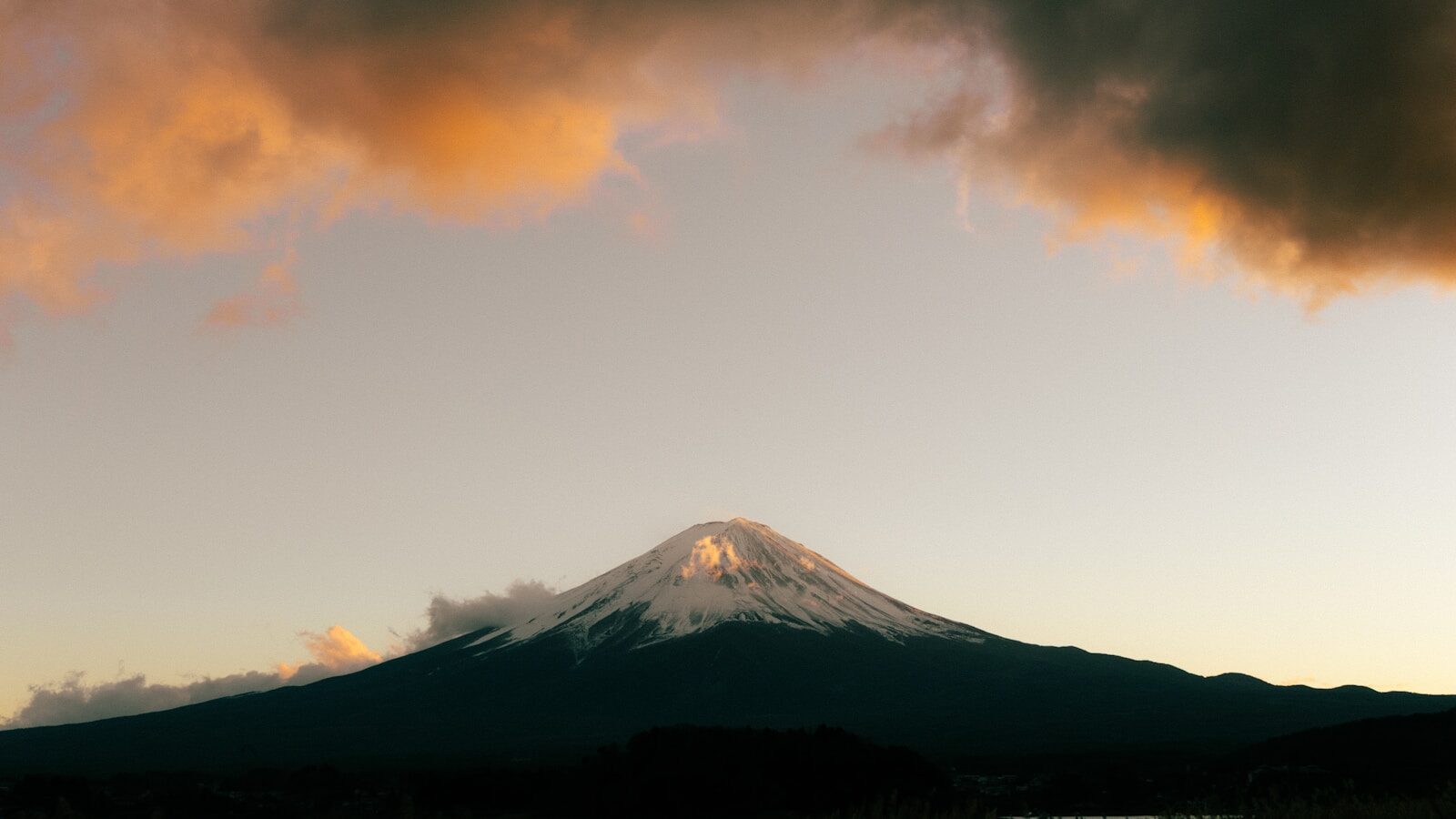 Snow-capped mount fuji at sunrise with vibrant clouds.